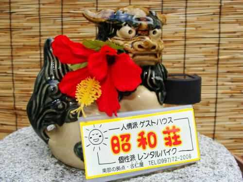 Eine Statue eines Dämons mit einem Schild drauf. in der Unterkunft Amami Guest House showa-so in Setouchi