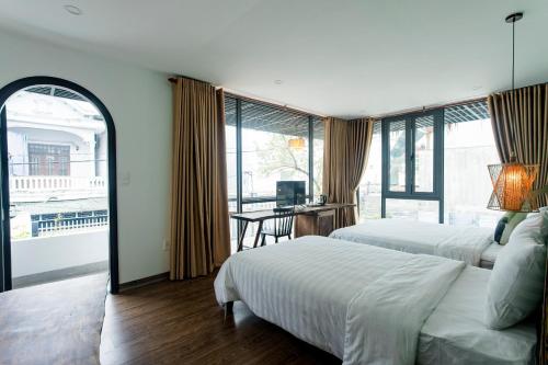 a bedroom with two beds and a table with a desk at Life Boutique Hotel in Hue
