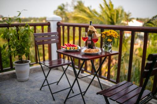 a table with glasses of wine and snacks on a balcony at Hoi An Riverside Villas & Apartments in Hoi An