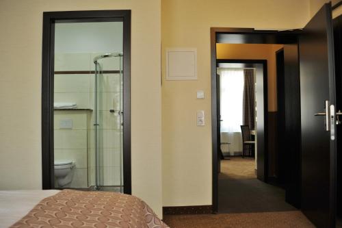 a bedroom with a shower and a bed and a bathroom at Hotel Atlas Halle in Halle an der Saale