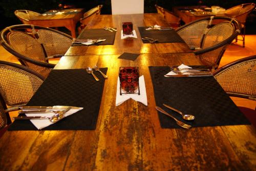 Una mesa de madera con servilletas y utensilios negros sobre ella. en Puetz Travels Beach Resort, en Wayikkal