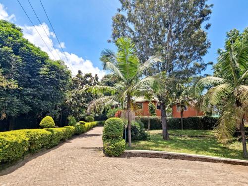 a garden with palm trees and a house at Africa Safari Arusha in Arusha