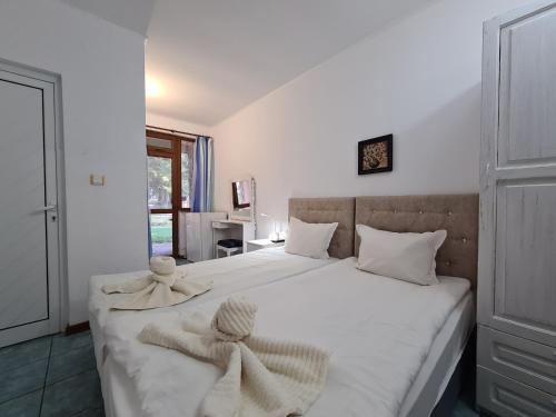 a bedroom with a large white bed with towels on it at Vila Kalvachevi in Tsigov Chark