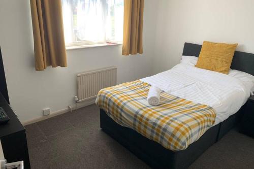 um quarto com uma cama com um cobertor amarelo e branco em 'The Rockingham' 4 double beds, Netflix TVs, WIFI, parking em Corby