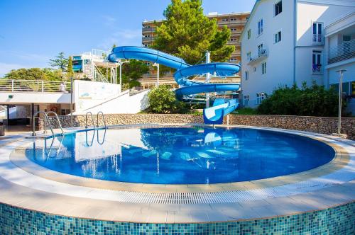 - une piscine avec un toboggan bleu dans l'établissement Villa Tamaris - Hotel Resort Dražica, à Krk