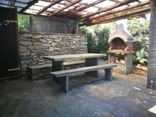 una mesa de picnic y un horno de pizza en un patio en Rustico Bietto, en Cevio