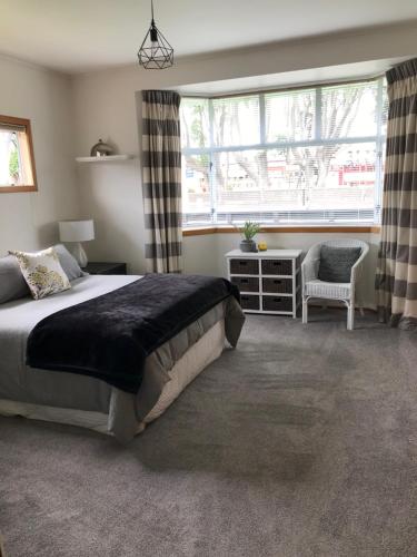 um quarto com uma cama, uma cadeira e uma janela em Fitzroy Gem em New Plymouth