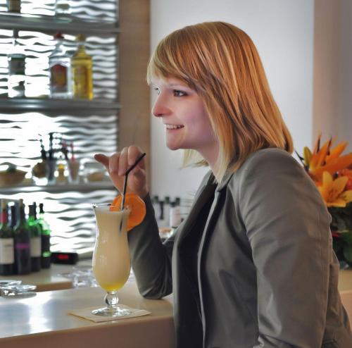 a woman sitting at a counter with a drink at Hotel Atlas Halle in Halle an der Saale
