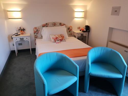 a bedroom with a bed and two blue chairs at Albergo Al Moretto in Castelfranco Veneto