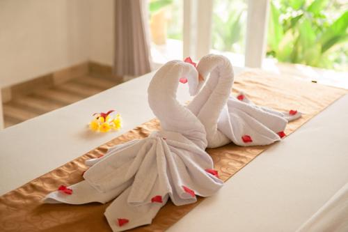 two towel swans are sitting on a table at kaje cottage & restaurant in Nusa Penida