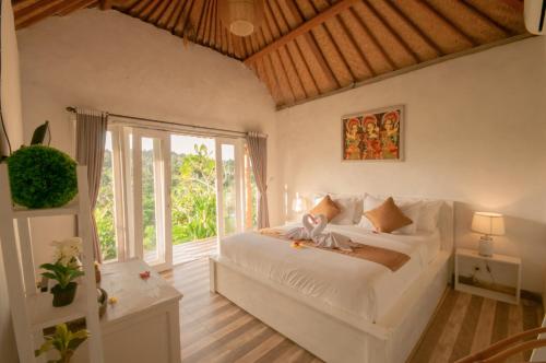 a bedroom with a white bed and a large window at kaje cottage & restaurant in Nusa Penida