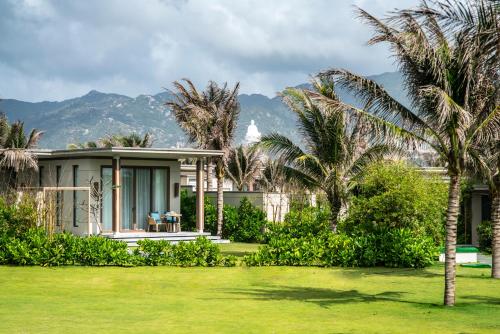 a house with palm trees in front of it at Maia Resort Quy Nhon in Quy Nhon