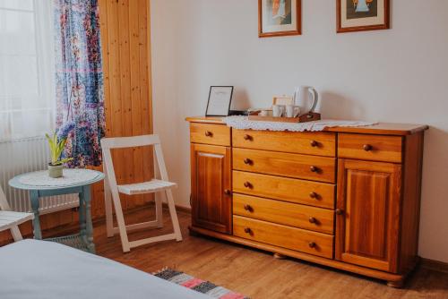 a bedroom with a wooden dresser and a chair at Dom Gościnny Sowia Stópka in Miłomłyn