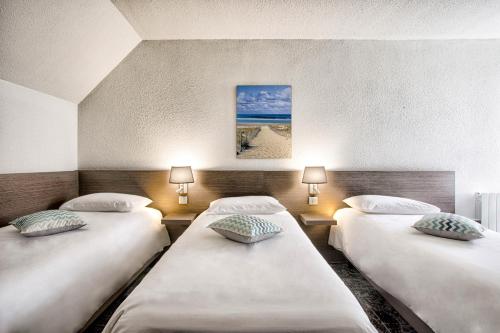 two beds in a room with two lamps at Mercure Cabourg Hôtel & Spa in Cabourg