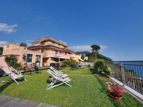 a house with chairs on the lawn near the water at Hotel Residence Mondial in Moneglia