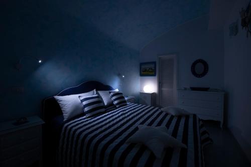 a blue bedroom with a bed with striped sheets and pillows at Atrani Apartments on the Amalfi Coast, air-purified, close to the beach and easy access in Atrani