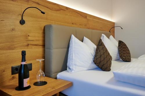 a bed with a bottle of wine on a table at Landgasthof Mayr in Steyr