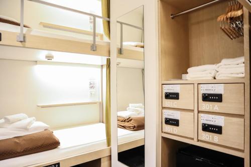 a room with a bed, shelves, and other items at WeBase Hiroshima in Hiroshima