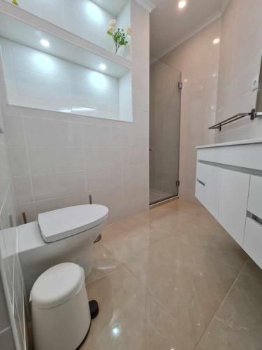 a white bathroom with a toilet and a sink at Albur Beach House in Alvor
