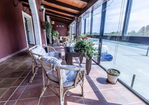porche con sillas, mesa y ventanas en Hosteria Tierrallana by Juypehotel, en El Provencio