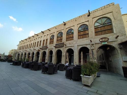 杜哈的住宿－艾卡瑞斯酒店，前面设有桌椅的建筑