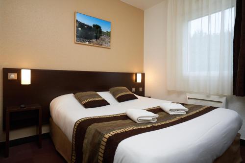 een hotelkamer met een groot bed met handdoeken erop bij Kyriad Limoges Sud - Feytiat in Feytiat