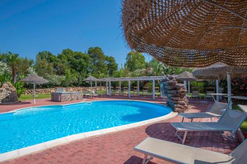 a swimming pool with two chairs and an umbrella at Hotel Rurale Orti di Nora & SPA in Santa Margherita di Pula