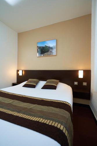 a bedroom with a large bed with two pillows at Kyriad Limoges Sud - Feytiat in Feytiat