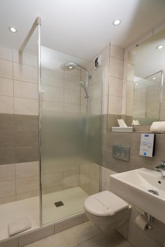 a bathroom with a shower and a toilet and a sink at Kyriad Limoges Sud - Feytiat in Feytiat