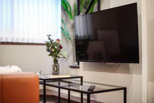 a living room with a tv and a vase of flowers on a table at Ken's Place Azabudai in Tokyo