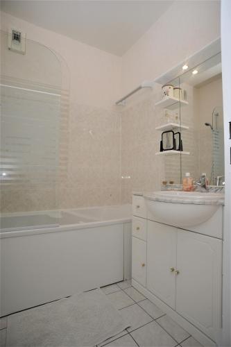 La salle de bains blanche est pourvue d'un lavabo et d'une baignoire. dans l'établissement L'Esplanade, à Dieppe