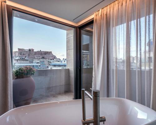 a bath tub in a bathroom with a window at Niche Hotel Athens in Athens