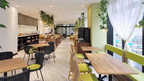 a restaurant with wooden tables and green chairs at Green Rich Hotel Tottori Ekimae (Artificial hot spring Futamata Yunohana) in Tottori