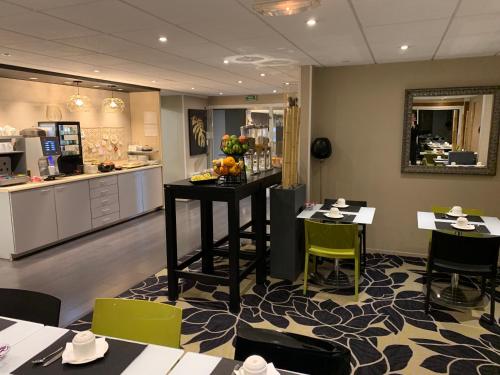 a room with tables and chairs and a kitchen at Mercure Cabourg Hôtel & Spa in Cabourg