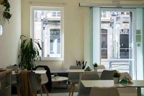 Habitación con mesas, sillas y ventanas. en Alda Alborán Rooms en A Coruña