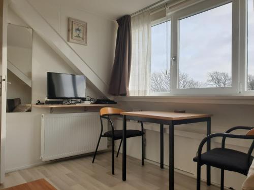 a room with a table and chairs and a window at Homestay Texel in Den Burg
