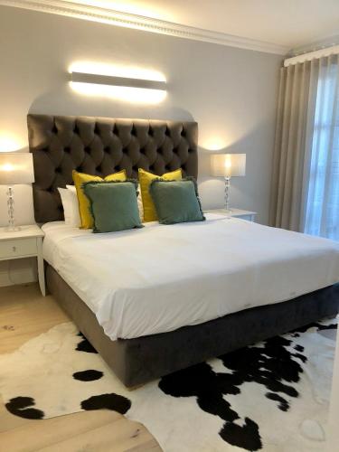 a bedroom with a large bed with yellow and green pillows at Romney Park Luxury Apartments by The Stay Collection in Cape Town