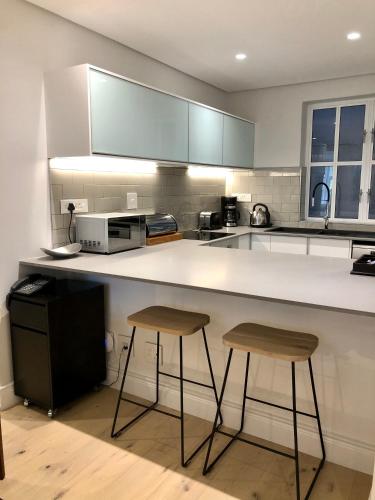a kitchen with two bar stools and a counter at Romney Park Luxury Apartments by The Stay Collection in Cape Town