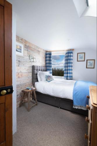 a bedroom with a large bed and a window at Niver Dew Holiday Cottage in Lower Boscaswell