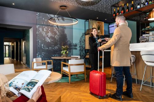 a man and a woman with a red suitcase in a restaurant at Mercure Saint Omer Centre Gare in Saint-Omer