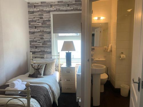 a bedroom with a bed and a sink and a mirror at Arran Lodge B&B in Torquay