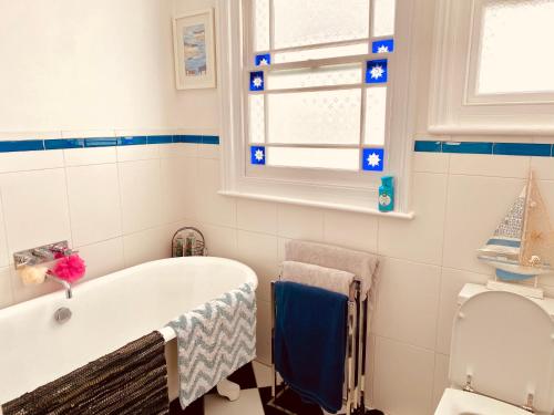 a bathroom with a tub and a window and a toilet at Alexandra Beach Haven in Worthing