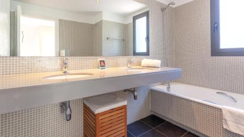 ein Badezimmer mit zwei Waschbecken und einer Badewanne und einem Spiegel in der Unterkunft VISTA ALEGRE in Tamariu
