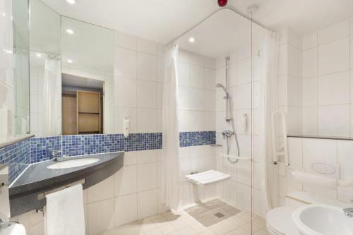 ein Bad mit einer Dusche, einem Waschbecken und einem WC in der Unterkunft Holiday Inn Express Royal Docks, an IHG Hotel in London