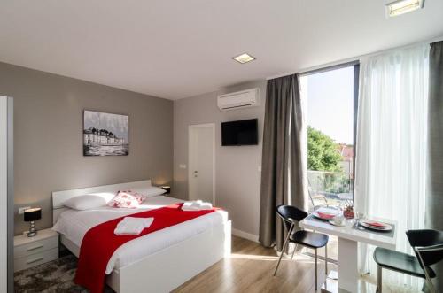 1 dormitorio con cama, escritorio y ventana en Apartments ZoomZoom, en Dubrovnik