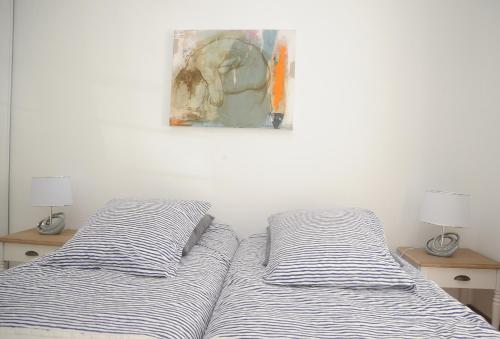 un lit avec deux oreillers et un tableau au mur dans l'établissement L'Esplanade, à Dieppe
