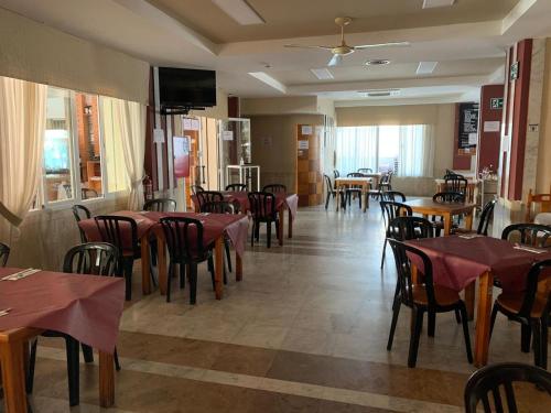 comedor con mesas y sillas y TV en Hotel Estrella Del Mar en Motril