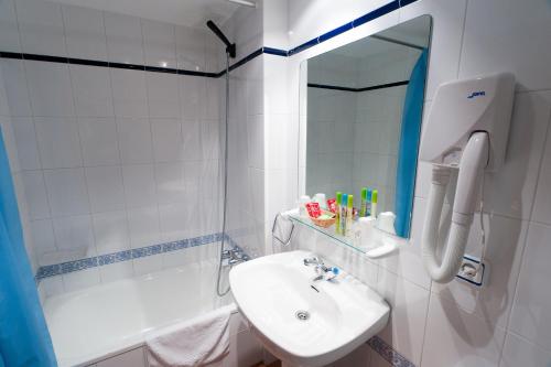 a white bathroom with a sink and a mirror at Hotel Costa de Rodiles in Selorio