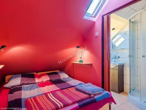 POKOJE GOŚCINNE SURFINIA في غدانسك: غرفة نوم بحائط احمر مع سرير ومغسلة