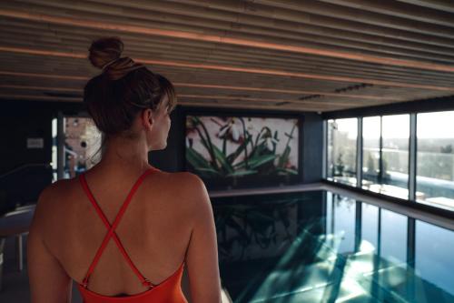 VALO Hotel & Work Helsinki في هلسنكي: وجود امرأة بملابس السباحة تقف بجانب حمام السباحة